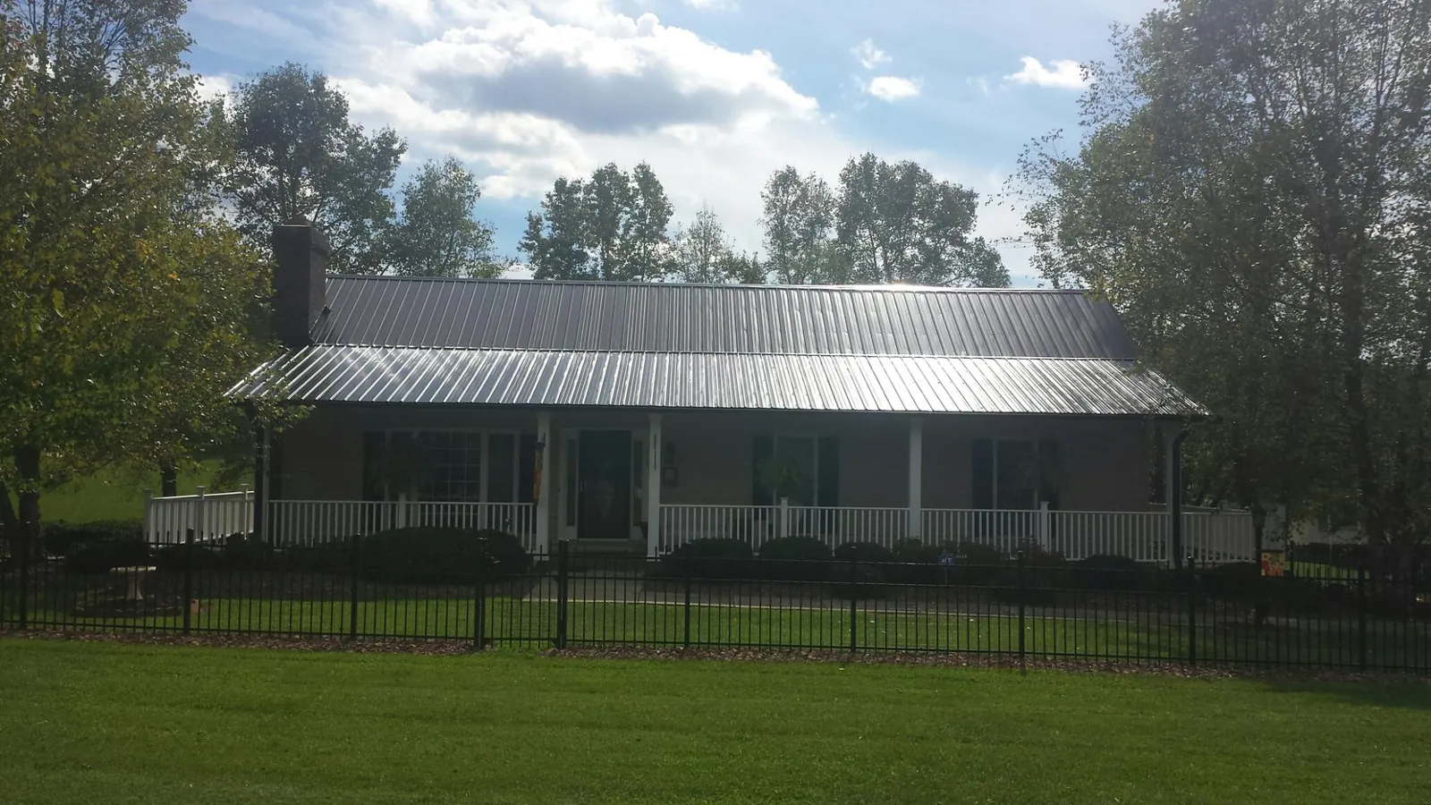 Gray metal roof on a brick ranch with a full width front porch — Gutter Guard Installation work by our crew in Random Lake